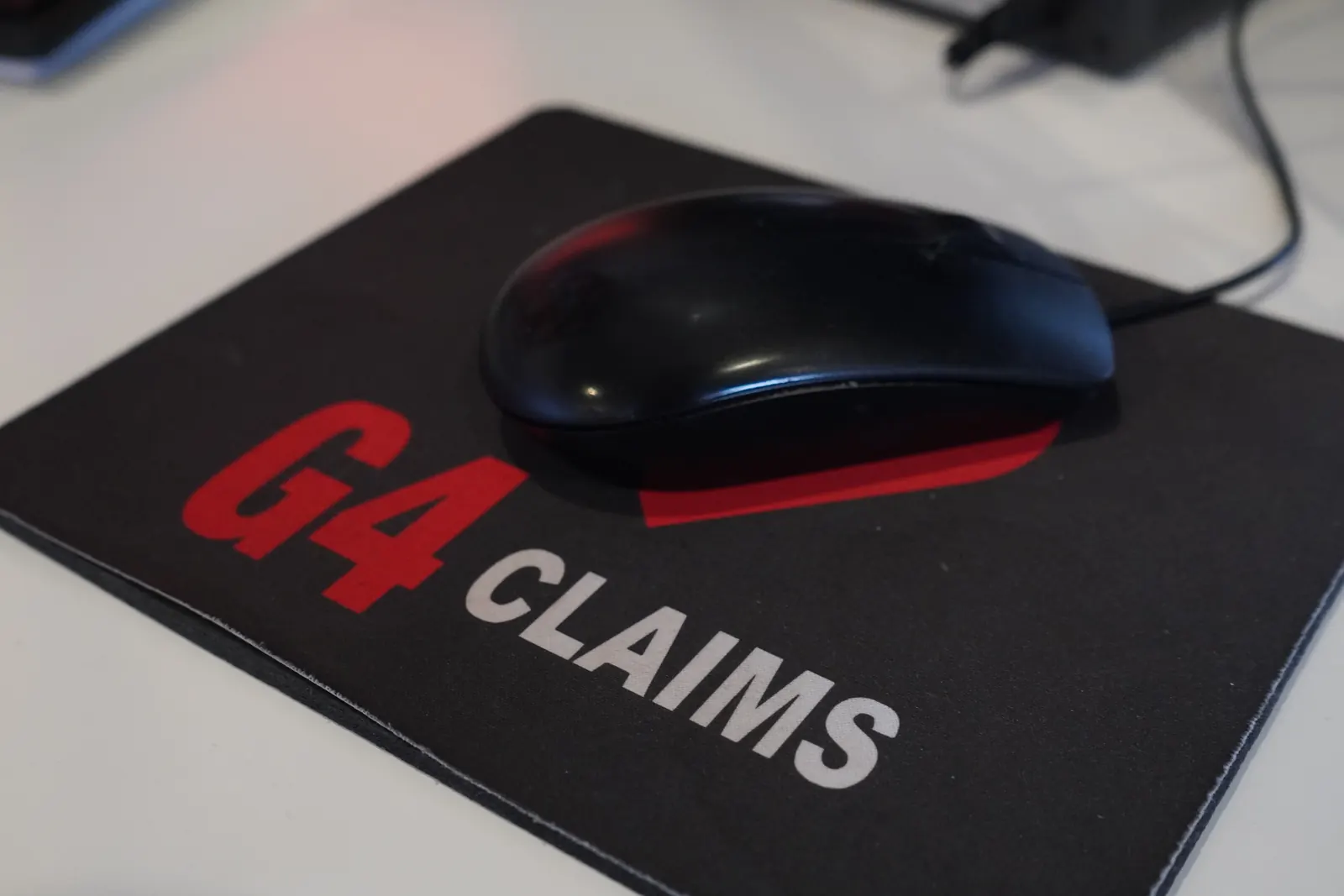 A G4 Claims branded mouse mat and mouse on a desk at Claims HQ
