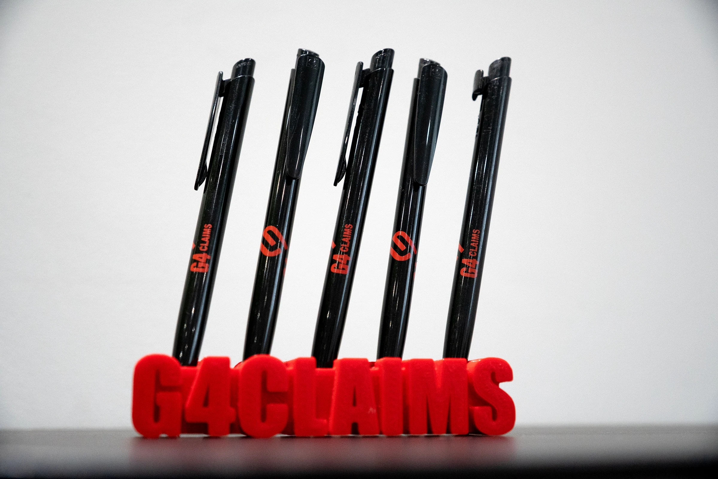 A row of G4 Claims pens in a red G4 Claims holder